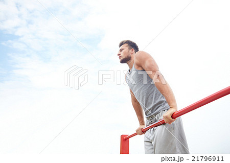 young man exercising on horizontal bar outdoors 21796911