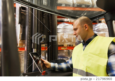 man with tablet pc operating forklift at warehouse 21796960