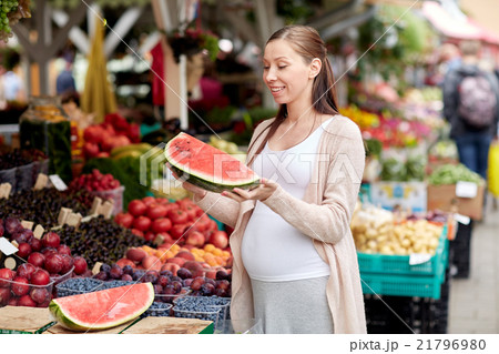 pregnant woman holding watermelon at street market pregnant woman holding watermelon at street market 21796980