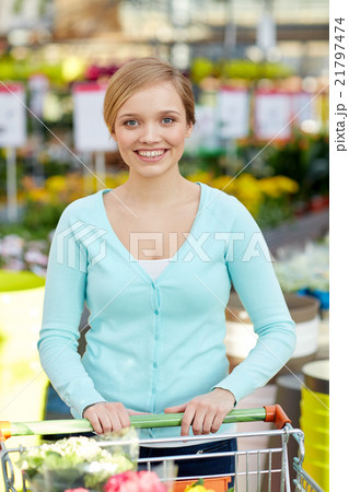 happy woman with shopping cart and flowers in shop 21797474