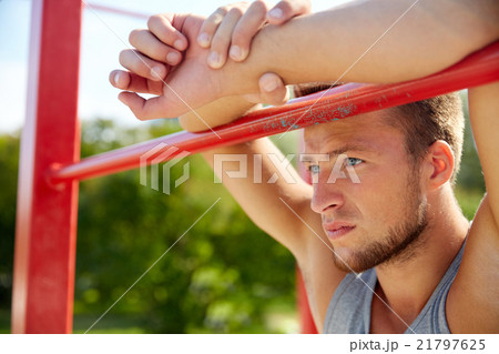 young man exercising on horizontal bar outdoors 21797625