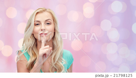 beautiful young woman holding finger at her lips 21798125
