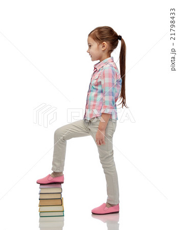 happy little girl stepping on book pile happy little girl stepping on book pile 21798433