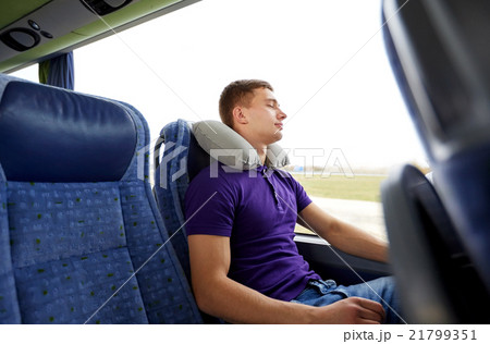 happy young man sleeping in travel bus with pillow 21799351
