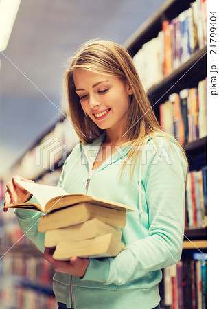 happy student girl or woman with book in library 21799404