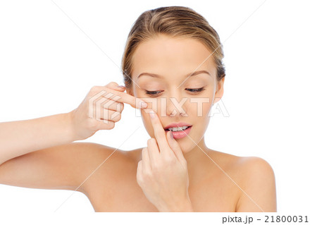 young woman squeezing pimple on her face 21800031