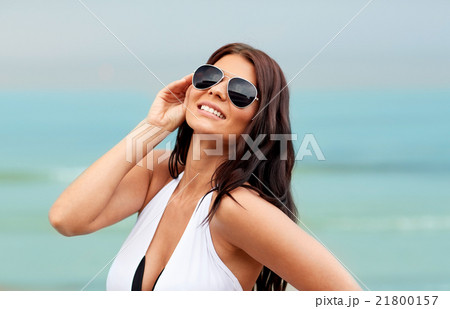smiling young woman with sunglasses on beach 21800157