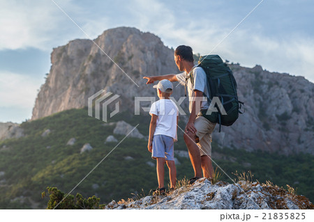 Father with backpack and son in the mountains Father with backpack and son in the mountains 21835825