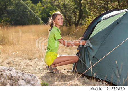 Smiling teenager girl setting a tent Smiling teenager girl setting a tent 21835830