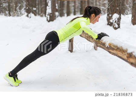 Fit woman exercising in woods doing push ups on a 21836873