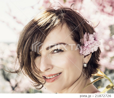 Young caucasian brunette posing with sakura flowers in sunlight Young caucasian brunette posing with sakura flowers in sunlight 21872726