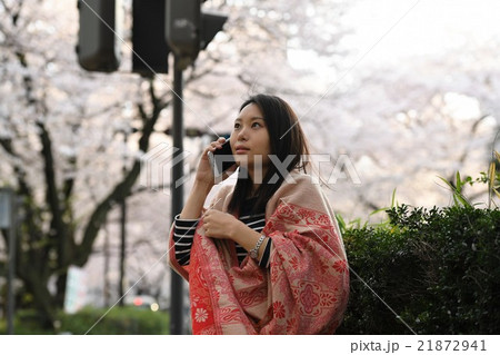 桜並木　屋外の路地で携帯電話で会話する女性 21872941