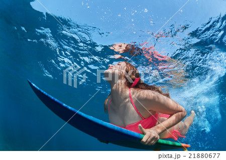 Surfing girl with board dive under ocean wave 21880677