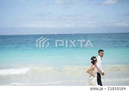 ビーチウェディングをする新郎新婦 21910164