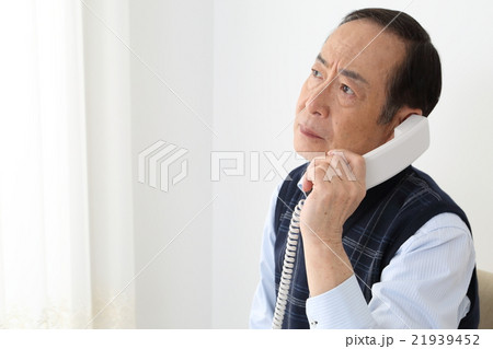 電話をするシニア男性 眉間にシワ の写真素材