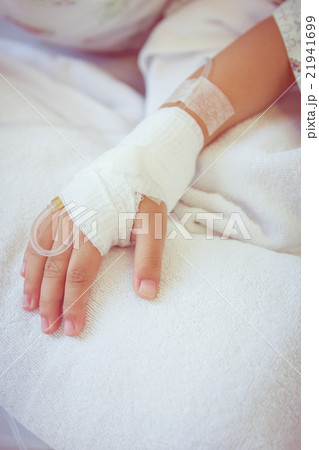 Saline intravenous drip in a child's patient hand. 21941699
