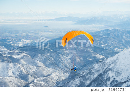 Paraglider launching from snowy slope Paraglider launching from snowy slope 21942734