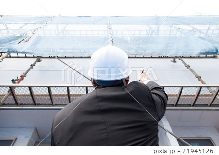 建物の確認をするヘルメット姿の男性 21945126