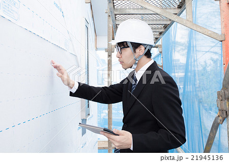 足場で建物の確認をするヘルメット姿の男性 21945136