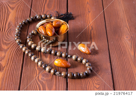 Dates fruit and rosary still life, on a brown Dates fruit and rosary still life, on a brown 21976417