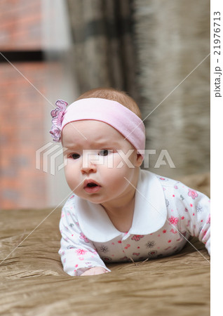 Baby girl lying on belly and grimacing Baby girl lying on belly and grimacing 21976713