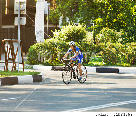 Female cyclist rides a racing bike on road Female cyclist rides a racing bike on road 21981568