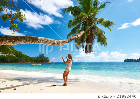 Woman in blue dress swinging at beach 21982440