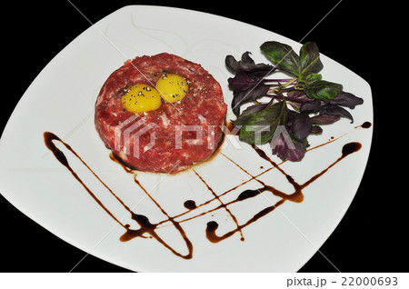 Steak Tartar. Ground beef and raw egg with herbs and spices on a 22000693