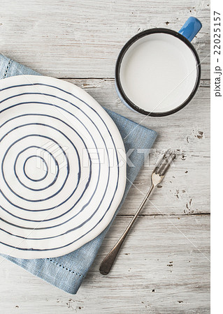 Ceramic plate with fork and cup of milk on table 22025157