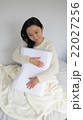 枕を抱きしめながら微笑む女性 22027256