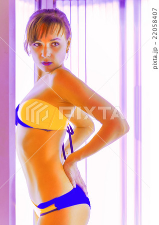 Slim young woman standing in solarium getting sun tan Slim young woman standing in solarium getting sun tan 22058407