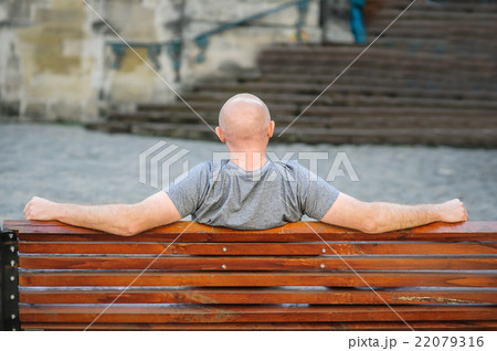 man sits on a bench in city man sits on a bench in city 22079316