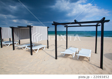 Different parasols and sun loungers on the beach  22093852