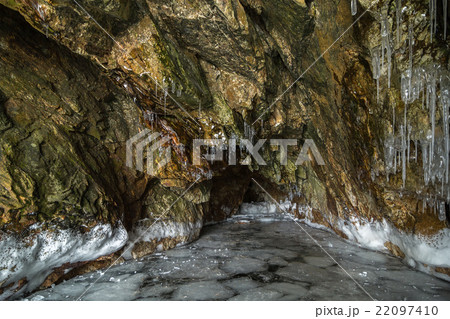 Multicolored stone cave in the cliff with icicles. Multicolored stone cave in the cliff with icicles. 22097410