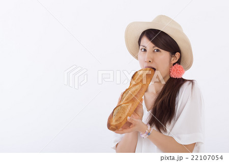 フランスパンを食べる可愛い女性の写真素材