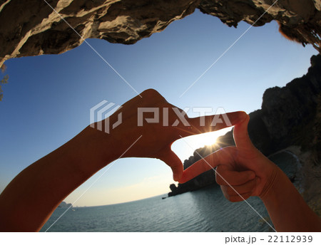 frame making of hands against seaside sunset 22112939