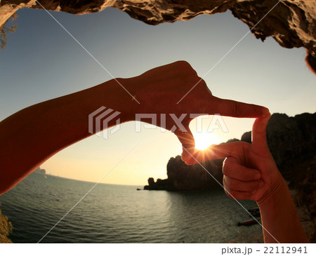 frame making of hands against seaside sunset 22112941