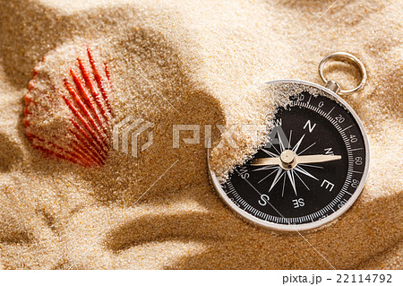 Black compass and sea shell in sand 22114792