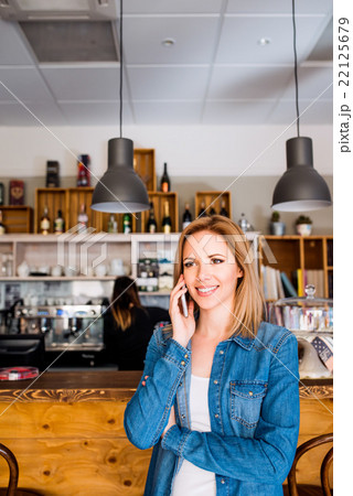 Blond woman standing at the bar, talking on phone 22125679