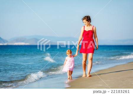 Mother and daughter walking on the beach 22183261