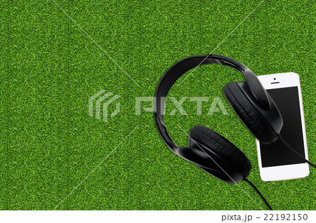 Smartphone with black earphones on the grass Smartphone with black earphones on the grass 22192150