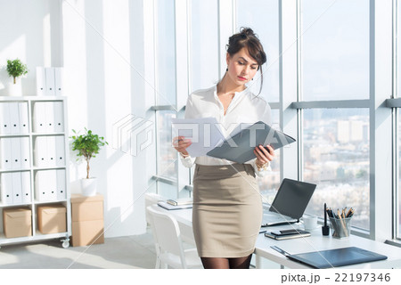 Young female employee, standing in office, wearing Young female employee, standing in office, wearing 22197346