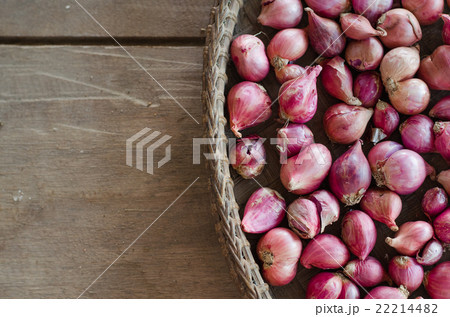Several shallots in  basket on wooden table. 22214482