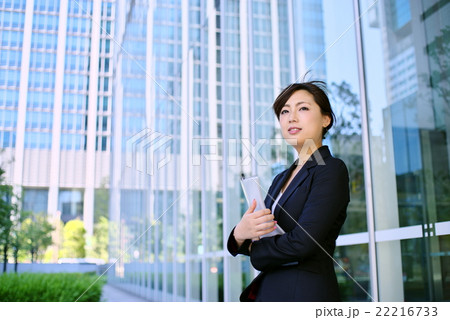 働く女性　オフィス街 スーツ姿で資料を手に a 22216733