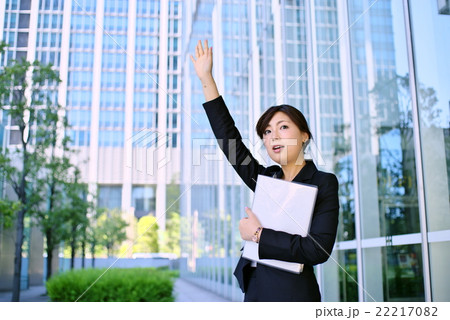 働く女性 スーツ姿で手を上げ合図する 資料を手に Eの写真素材