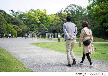 爽やかな緑の公園を散歩する夫婦の写真素材