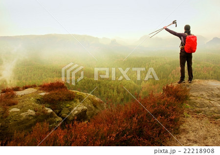 Adult backpacker with poles in the air on rock Adult backpacker with poles in the air on rock 22218908