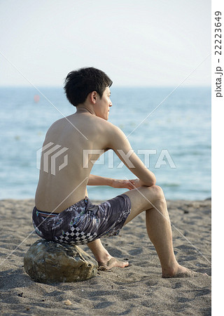 ビーチに座る若い男性の写真素材