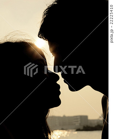 夕日の海でキスするカップルの写真素材