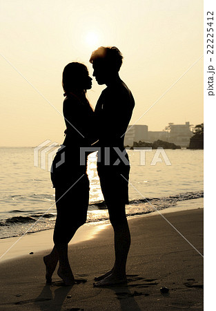 夕日の海でキスするカップルの写真素材